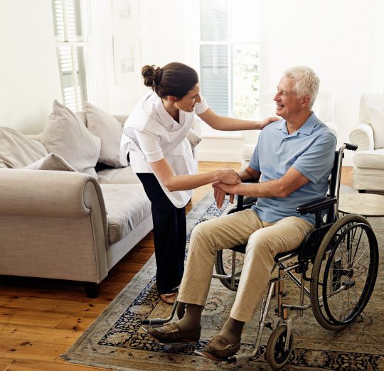 Shot of a caregiver helping a senior man in a wheelchair at home.